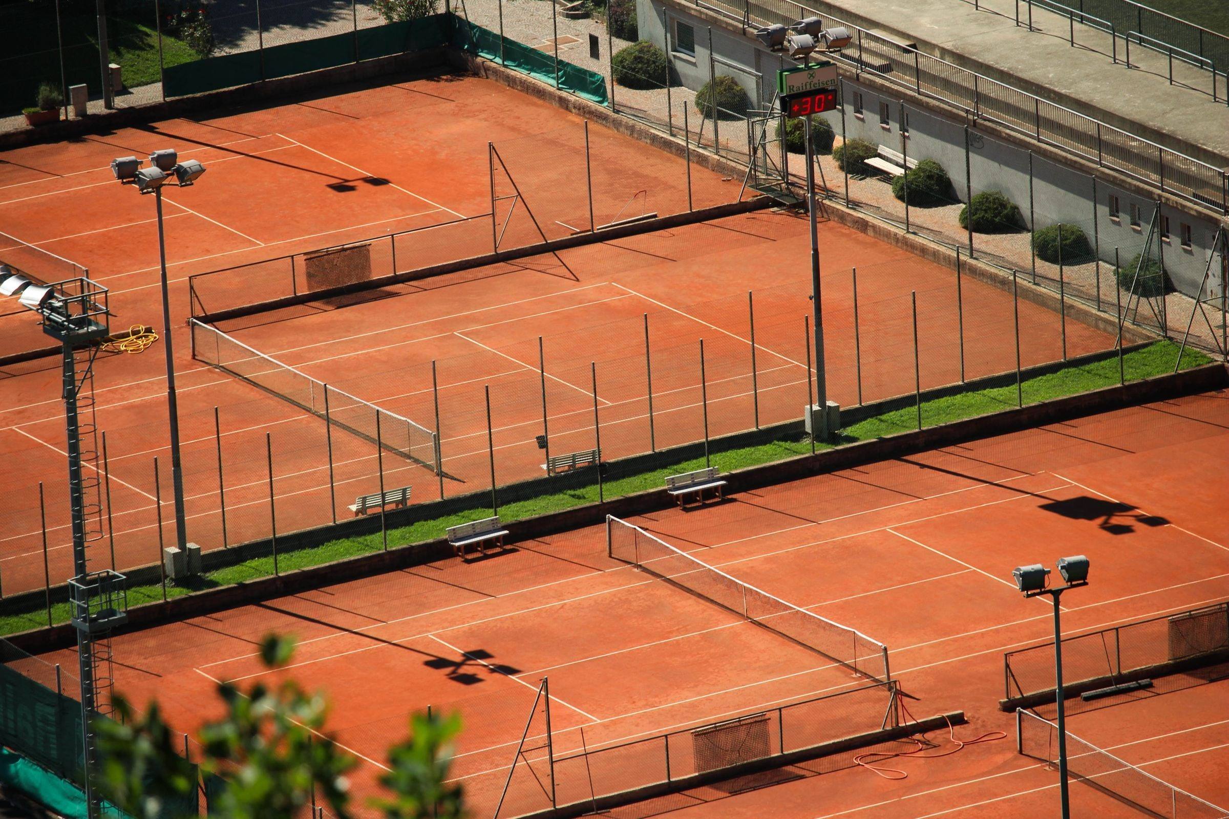 Courts de tennis en terre battue vus d’en haut, filets et lignes blanches